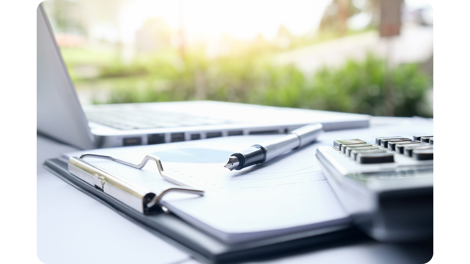 Laptop, daneben ein Klemmbrett mit einem Füller und einer Tastatur angelehnt